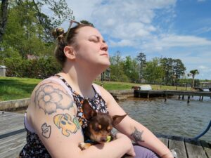 Sam sitting on a pier holding Poops (our dog) in South Carolina