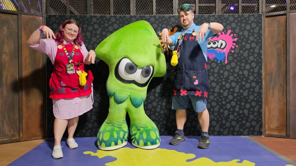 sam and steve stand on either side of a squid posing with arms up, and three fingers dangling down